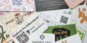 Picture of an assortment of business cards on a table with text.